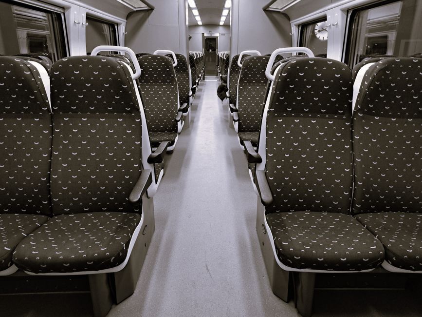 A professional cleaning technician from Old Oak Common Carpet Cleaners is performing deep surface cleaning on a beige fabric upholstered chair, using a handheld steam or spray cleaning device. The dev